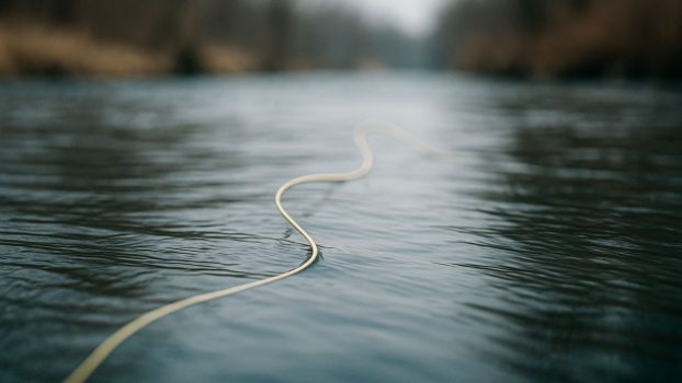 Línea de pesca a mosca flotando en el río con un pliegue que muestra la tensión del agua