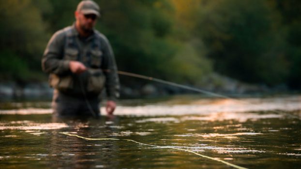Pescador a mosca observando la línea sobre la superficie del río antes de lanzar