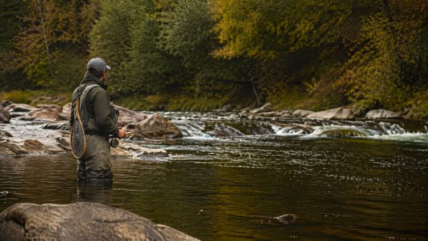 Pescador en el río observando el agua antes de decidir dónde lanzar